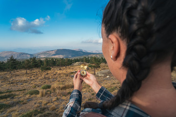 Young Traveling Woman wearing braids and backpack, standing in the wild with compass on the mountain.