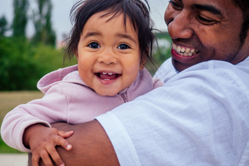 transnational interracial afro father spinning around circles at the park mixed race baby girl