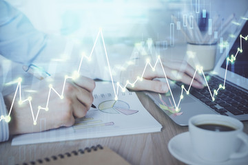 Multi exposure of stock market graph with man working on laptop on background. Concept of financial analysis.