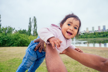 transnational interracial afro father spinning around circles at the park mixed race baby girl