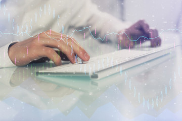 Double exposure of graph with man typing on computer in office on background. Concept of hard work....
