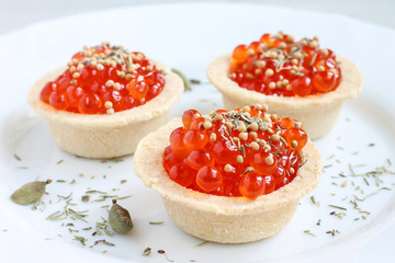 Rad caviar. Red caviar in tartlets on white plate close up