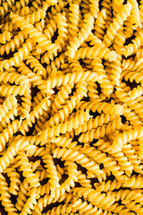 Uncooked whole wheat fusilli italian pasta background, selective focus. Pasta pattern. Food background. 