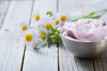 pink cosmetic cream and white herbal flowers on old rusty wooden table background