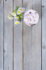 pink cosmetic cream and white herbal flowers on old rusty wooden table background