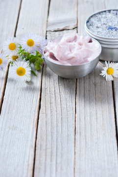 Pink Moisturizer Cream, Blue Bath Salt And White Flowers On Natural Rusty Wood Table