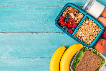 Lunch boxes with food ready to go for work or school. sandwich, vegetables, nuts, berries, eggs and yogurt.