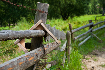 Old wooden fence in the mountains. Forest and tall trees. Mountains and hills. Summer