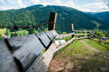 Fototapeta na wymiar Old wooden fence in the mountains. Forest and tall trees. Mountains and hills. Summer