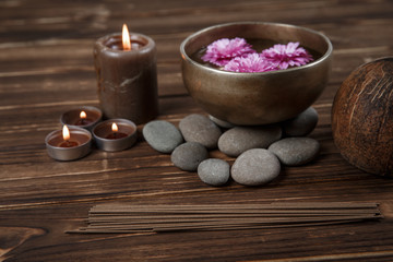 Singing bowl with candles with pebbles on dark wooden background