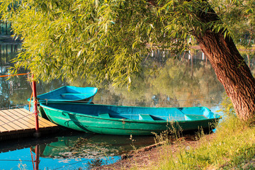 Two boats on the water. Two wooden boats in a pond under a tree in the setting sun