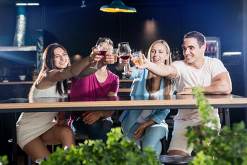 Cheerful friends in the pub. Drinking beer, wine and whisky, talking, having fun.