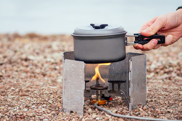 The pan with the porridge stands on the gas burner (Camping Stove). On the background of the river