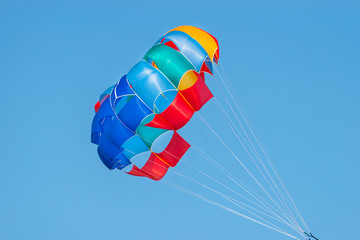 Close up shot of a colorful parachute used for parasailing pulled by a motorboat. - Powered by Adobe