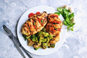 Fried chicken fillet. Broccoli and cauliflower. Baked chicken breast. Chicken and tomato. Food in a white plate on a light table background.