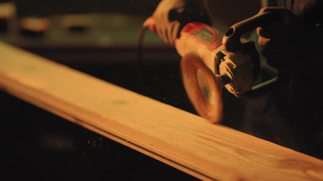 Woodworking, carpentering, craft, profession concept. Close up of man`s hands with power tool working with wood at sunset light