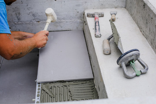 Tiler hands working on a new house entrance, local and professional handyman applying tiles to the steps.