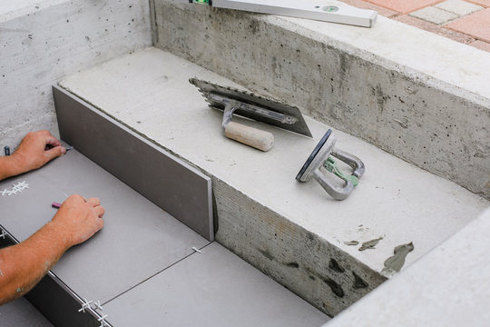Tiler hands working on a new house entrance, local and professional handyman applying tiles to the steps.