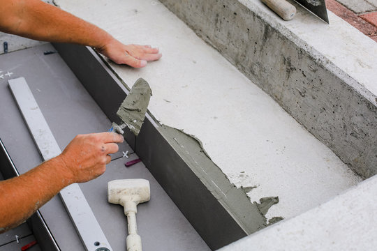 Tiler hands working on a new house entrance, local and professional handyman applying tiles to the steps.