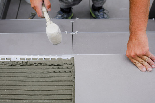 Tiler hands working on a new house entrance, local and professional handyman applying tiles to the steps.