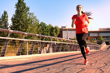 Obraz premium Beautiful young woman in sports clothing running while exercising outdoors.
