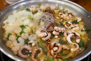 A close-up view of cuisine with various sea food ingredients such as shrimp, small octopus, and tripe.