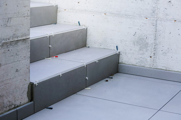 Laying new tiles on a concrete steps outside of a building