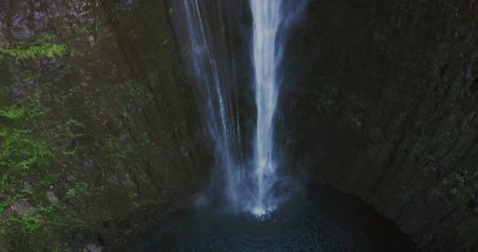 Aerial drone shot looking down on waterfall flowing into amazing natural pond, jurassic park concept