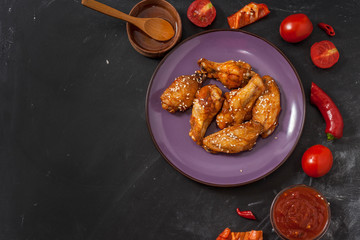 Fried juicy chicken wings marinated with honey, soy sauce, spices, sprinkled with sesame seeds on a...