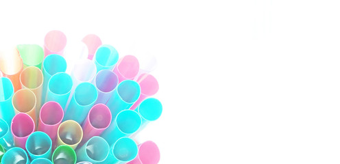 Unusual top view of many isolated multicolored plastic cocktail tubes on white background. Drinking straws of bright neon colors. Light effect. Copy space. Banner. Eco concept