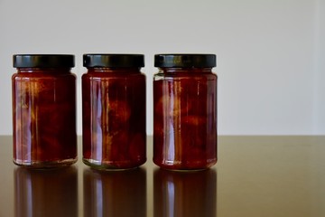 Fototapeta na wymiar three glass jars in a row with delicious coarse home made plum jam