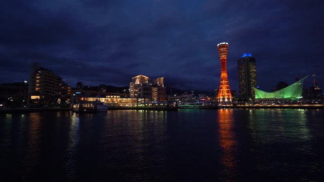 Slow panning night shot from the water of the city of Kobe in Japan showing the tower and skyscrapers