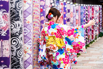 Kimono women takes picture with Kimono Forest Different kimono fabrics in transparent tubes at...