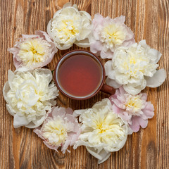 Fototapeta na wymiar Tea time. Flat lay over wooden background with peonies and a cup of tea
