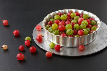 Gooseberries in a metal baking pan on a black background