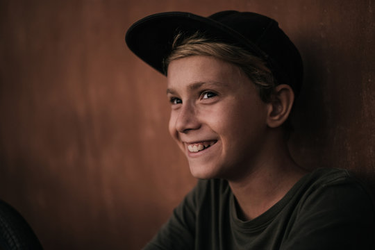 Portrait of a beautiful happy trendy boy. Image of a kid with rapper hat. Caucasian blonde young smiling man joyful and friendly in casual look. Warm filter. Youth fun happiness positive concept.