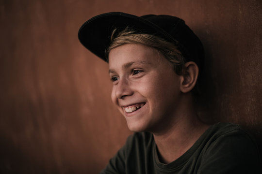 Portrait of a beautiful happy trendy boy. Image of a kid with rapper hat. Caucasian blonde young smiling man joyful and friendly in casual look. Warm filter. Youth fun happiness positive concept.