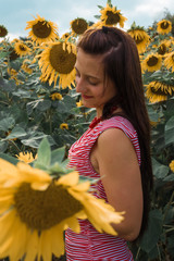 woman in a sunflower field looks down dreamily © funkenzauber