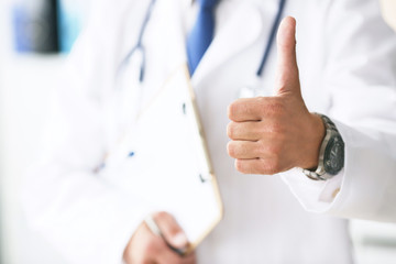 Close up of male doctor showing thumbs up gesture. Health care, people and medicine concept. Operation completed successfully