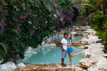 Couple smiling. Happy couple on vacation. Multiethnic couple at the swimming pool. Swimming pool surrounded by pink bougainvillea flowers.