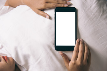 Asian Woman's hands using smartphone with blank screen in bedroom at morning.