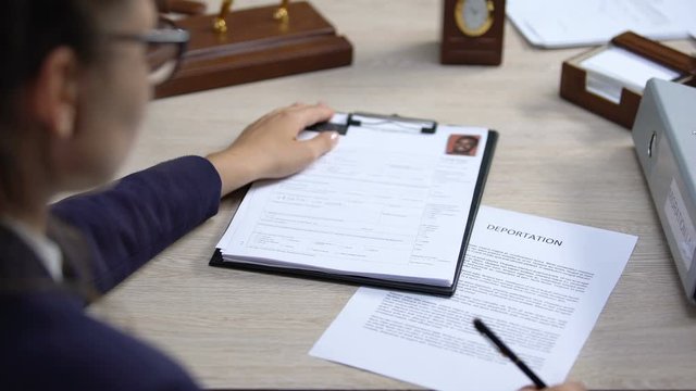 Employee looking through visa application and signing deportation document