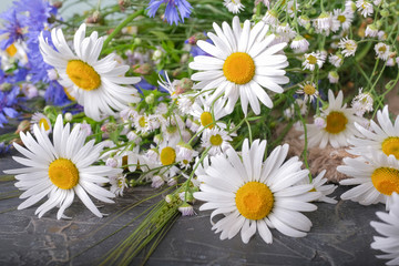 Obraz premium A bouquet of daisies and cornflowers on a dark table.