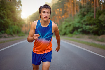 Fototapeta premium Caucasian middle age man athlete runs sunny summer day on asphalt road in the forest.