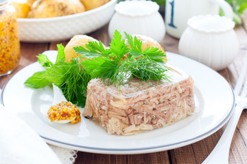 Homemade Aspic of turkey meat on a white plate with boiled potatoes, horizontal