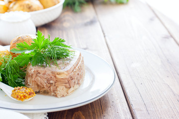 Homemade Aspic of turkey meat on a white plate with boiled potatoes and fresh herbs, horizontal, place for text
