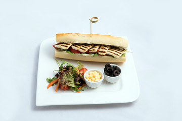 A high contrast Hero shot of a Grilled Halloumi cheese baguette with olives & salad on the side, on...
