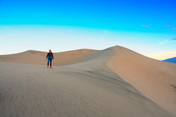 Fototapeta na wymiar Woman walking on the top of sand dunes