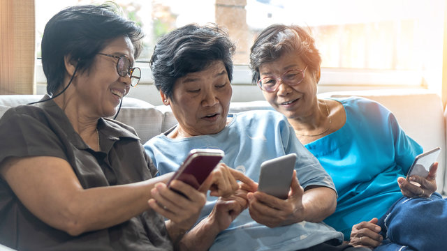 Ageing society concept with Asian elderly senior adult women sisters using mobile digital smart phone application technology for social media network among friends community via internet communication