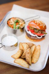 Tasty Hamburger with beef meat, potatoes, salad, tomato and onion